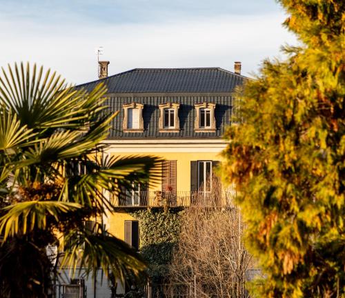 a large yellow house with a black roof at Hotel Casa Camilla in Verbania