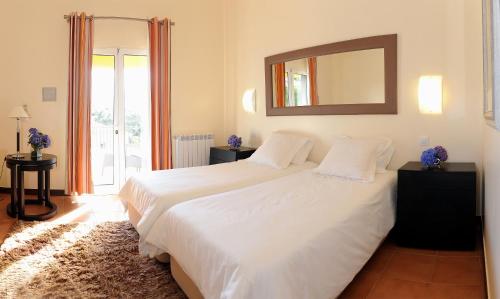 1 dormitorio con 1 cama blanca grande y espejo en Quinta Da Cova Do Milho, en Santo da Serra