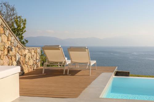 two chairs sitting on a deck next to a swimming pool at Thalasses Villas Skiathos in Skiathos Town