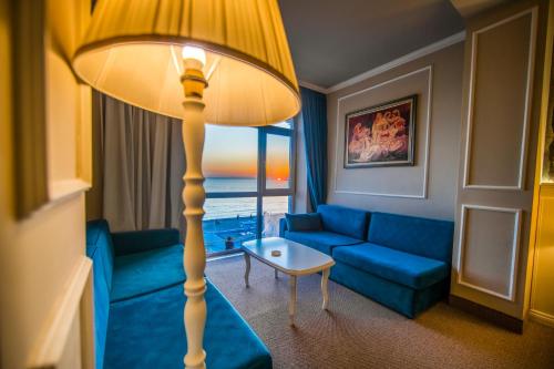 a living room with a blue couch and a floor lamp at Adriatik Hotel, BW Premier Collection in Durrës