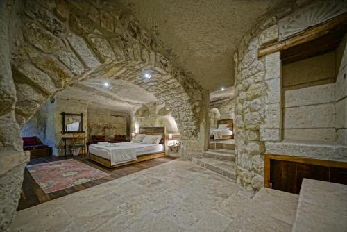 a bedroom with a bed and a stone wall at Naraca Cave House in Goreme