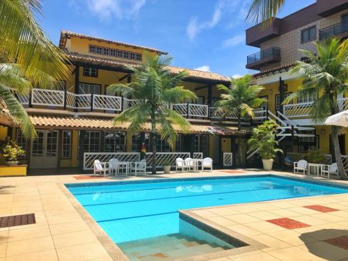 une piscine en face d'un bâtiment avec des palmiers dans l'établissement Hotel Mar de Cabo Frio, à Cabo Frio