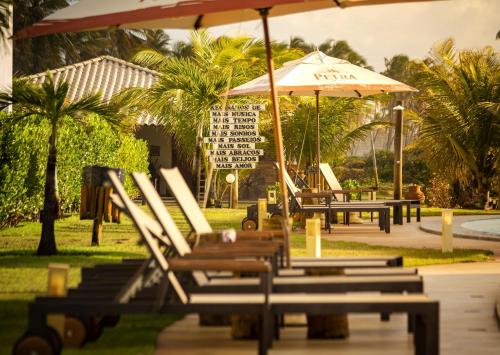 a group of lounge chairs and an umbrella at Tree Bies Resort - Oficial in Subaúma