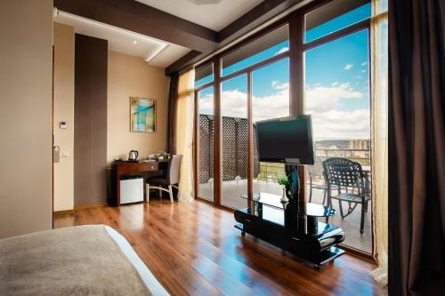 a room with a bed and a television and a balcony at Hotel Orion Tbilisi in Tbilisi City