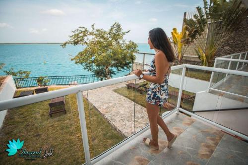 a woman walking on a balcony looking at the ocean at Hotel Awazul Bacalar in Bacalar