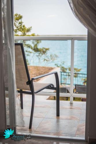 a swinging chair on a balcony with the view of the ocean at Hotel Awazul Bacalar in Bacalar