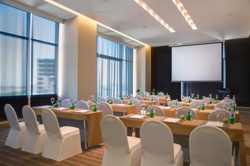 a conference room with tables and chairs and a projection screen at Erbil Rotana in Erbil
