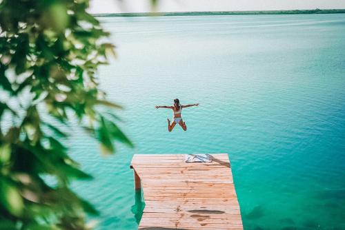 a woman jumping into the water from a dock at Hotel Awazul Bacalar in Bacalar