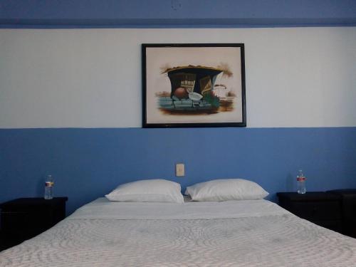 a bedroom with a bed with a blue wall and a picture at Pensión Aguayo in Puebla