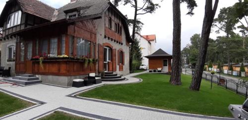 a house with a porch and a green lawn at Domek SERCE KRYNICY in Krynica Morska