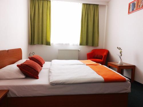 a bedroom with a bed and a red chair at Penzión Helios in Bratislava