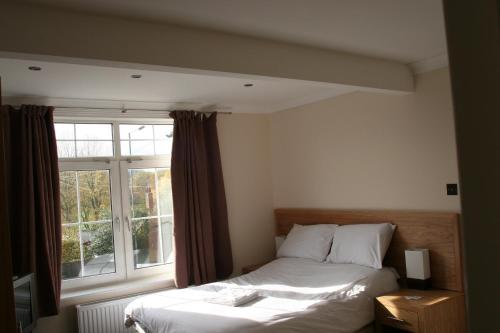 a bedroom with a bed and a window at Clifton Lodge Hotel in High Wycombe