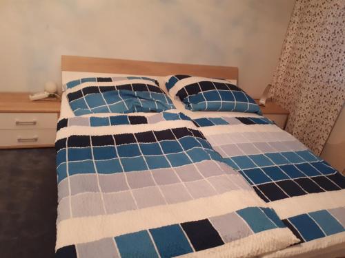 a bed with a blue and white blanket and pillows at Eventgasthaus Greil in Leitzersdorf