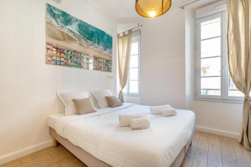 een slaapkamer met een wit bed met 2 kussens erop bij Agences des Résidences - Rue Commandant André in Cannes