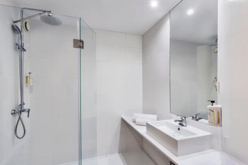 y baño blanco con lavabo y ducha. en B&B HOTEL Madrid Aeropuerto T1 T2 T3 en Madrid