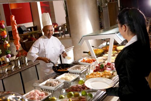 a man and a woman in a kitchen preparing food at Erbil Rotana in Erbil