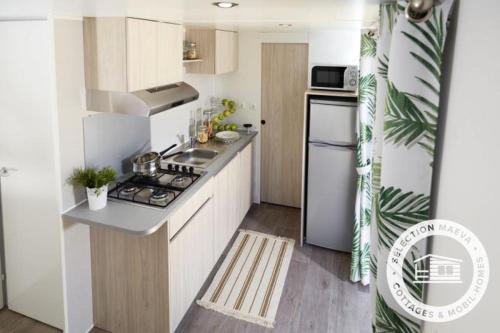 Il comprend une petite cuisine équipée d'une cuisinière et d'un réfrigérateur. dans l'établissement Camping Le Roussillon - Maeva, à Saint-Cyprien