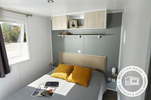 Dormitorio pequeño con cama con almohadas amarillas en Camping Le Roussillon - Maeva, en Saint-Cyprien