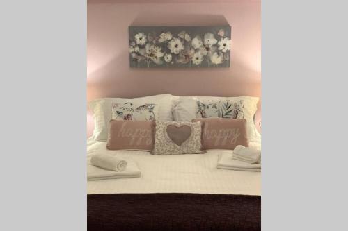 a white couch with pillows and a painting of flowers at Stunning Barn private hot tub Malvern & Worcester Sleeps 6 in Worcester