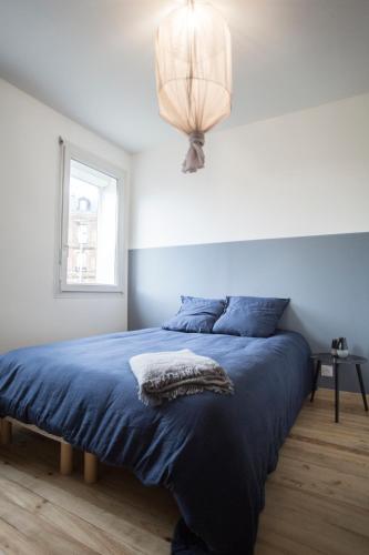 - une chambre avec un lit doté d'une couverture bleue et d'une lampe dans l'établissement Appartement de Paul & Marion, au Havre