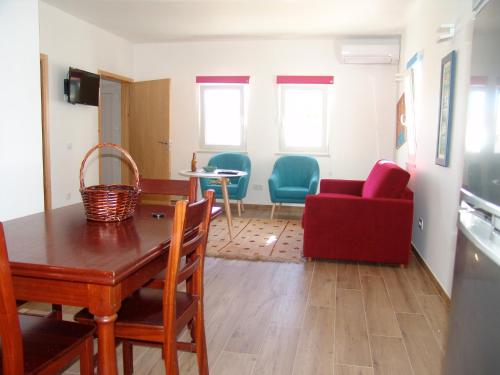 a living room with a table and a red couch at Herdade Rodrigo Afonso in São Teotónio