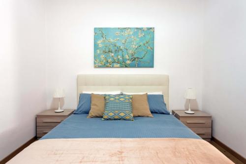 een slaapkamer met een blauw bed en 2 nachtkastjes bij Centre Apartment Grotte Bianche 2 in Catania