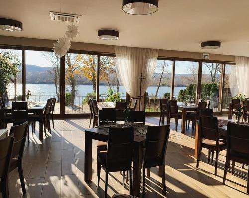 a restaurant with tables and chairs and a view of the water at Mlyn Penzion & Wellness in Radvaň nad Dunajom