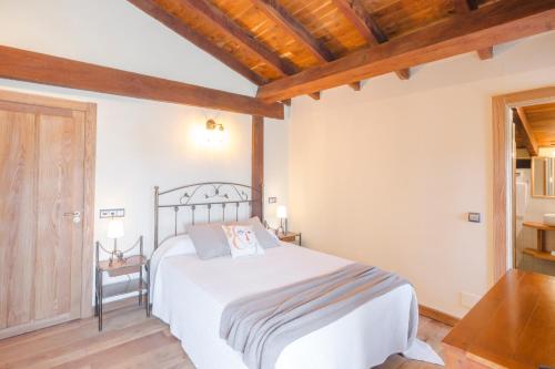 a bedroom with a white bed and a wooden ceiling at Posada Condado de la Mota in Mogro