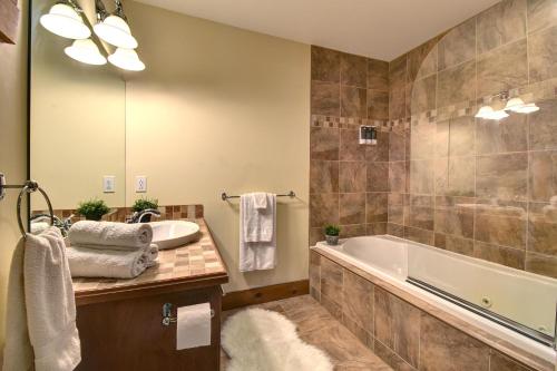 a bathroom with a tub and a sink at Chic Familiale, Relaxant avec spa en montagnes in Labelle