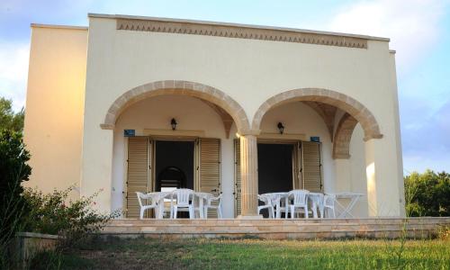 ein Gebäude mit weißen Tischen und Stühlen darauf in der Unterkunft Villa Carol in Torre Vado