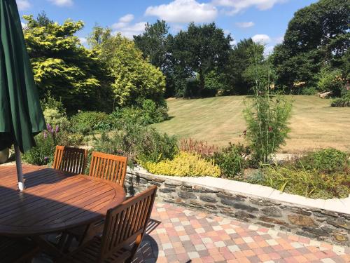 un patio con mesa y sillas y un jardín en Kerlogan, en Saint-Thois