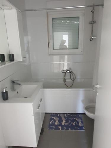 un bagno bianco con vasca e lavandino di Apartmani Matko a Nin