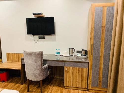 Cette chambre comprend un bureau avec une télévision et une chaise. dans l'établissement Hotel Sunstar Grand, à New Delhi