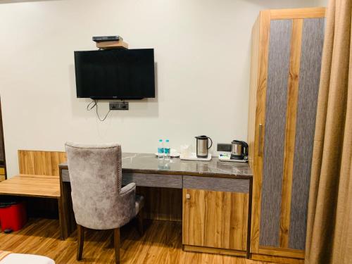 a room with a desk with a television and a chair at Hotel Sunstar Grand in New Delhi