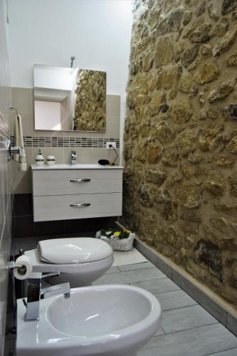 a bathroom with a white toilet and a stone wall at L'Antico Borgo di Segesta in Calatafimi