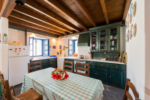 una cocina con armarios verdes y una mesa con flores. en Litsa Holiday Home, en Kalathos