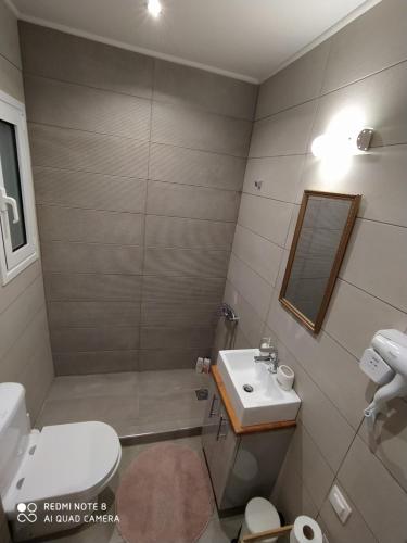 W łazience znajduje się umywalka, toaleta i lustro. w obiekcie Athens Lycabettus Luxurious Loft w Atenach