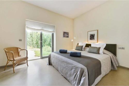 ein Schlafzimmer mit einem Bett, einem Stuhl und einem Fenster in der Unterkunft CAN COOL in Ibiza-Stadt