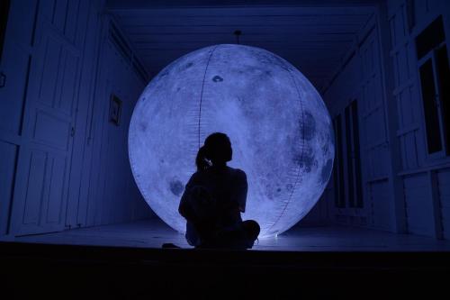 a woman sitting in front of a moon ball at One Chan Farmstay in Chanthaburi