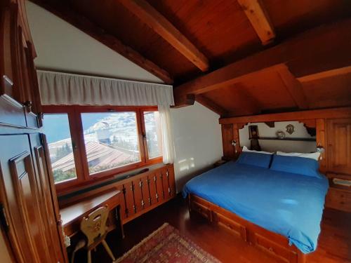 a bedroom with a blue bed and a window at Mansarda in chalet a Cortina in Cortina dʼAmpezzo
