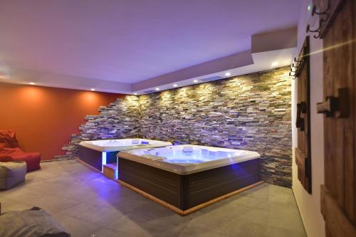 łazienka z 2 wannami w kamiennej ścianie w obiekcie Alp Hotel Dolomiti w mieście Dimaro