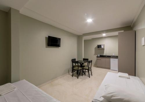 a bedroom with a bed and a table and chairs at Pousada Castellammare in Bombinhas