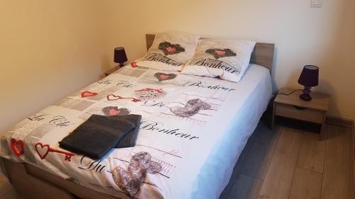 a bed with a white comforter and pillows on it at Appartement au pied des 3 Vallées in Moutiers