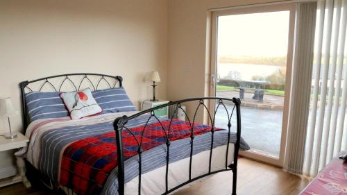 - une chambre avec un lit et une grande fenêtre dans l'établissement Emy Lake Studio, à Monaghan