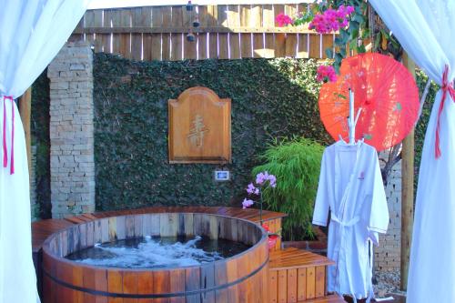 a hot tub in a garden with an umbrella at Pousada Ikabana in Pirenópolis