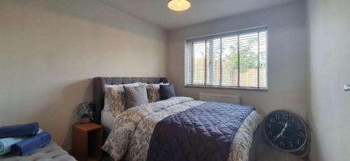 ein Schlafzimmer mit einem Bett, einem Fenster und einer Uhr in der Unterkunft Y Bwythyn in Holywell
