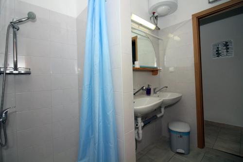 a bathroom with a blue shower curtain and a sink at Hostel Marko in Tisno