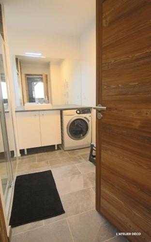 - une cuisine avec un lave-linge et un sèche-linge à côté d'une porte dans l'établissement Magnifique T5 Duplex de Grand Standing 120m2 neuf classé 4 étoiles pour 8 personnes en plein centre de Saint-Lary-Soulan, à Saint-Lary-Soulan