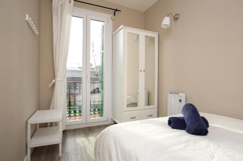 a white bedroom with a bed and a window at Valladolid 19 in Barcelona