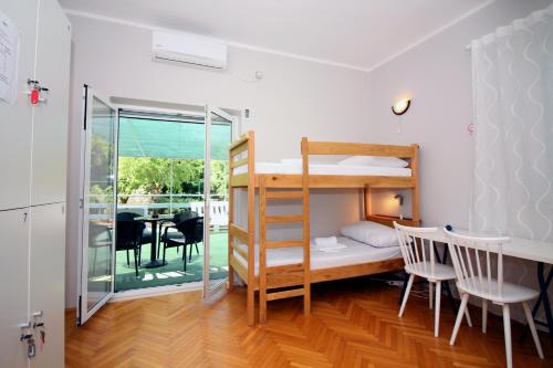 a room with a bunk bed and a table and chairs at Hostel Marko in Tisno